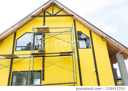 Painted facade with decorative timber boards forming half-timber look, external wall coating, finished plaster layer, color, renovation, final construction step. Painted facade with decorative timber boards forming half-timber look, external wall coating, finished plaster layer, color, renovation, final construction step. 138435703