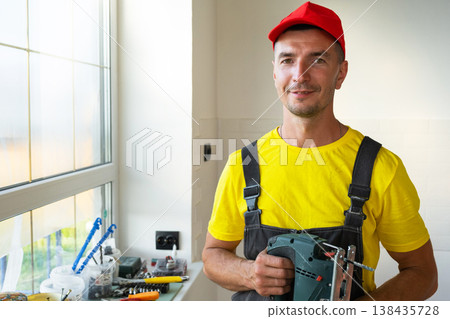 Builder portrait in work clothes, paint roller and drill tools, handyman services, renovation jobs, home repairs, expert home visit, construction business. Builder portrait in work clothes, paint roller and drill tools, handyman services, renovation jobs, home repairs, expert home visit, construction business. 138435728