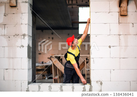 Measuring and marking window opening, preparation for new window installation, size check, construction fit, drywall and brick partition projects. Measuring and marking window opening, preparation for new window installation, size check, construction fit, drywall and brick partition projects. 138436041