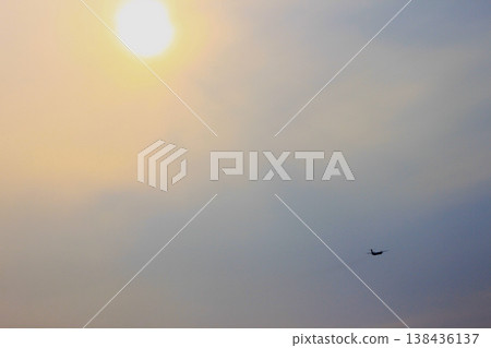 在傍晚的天空中，一架客機的輪廓清晰可見，夕陽西下，飛機尾跡清晰可見。 138436137