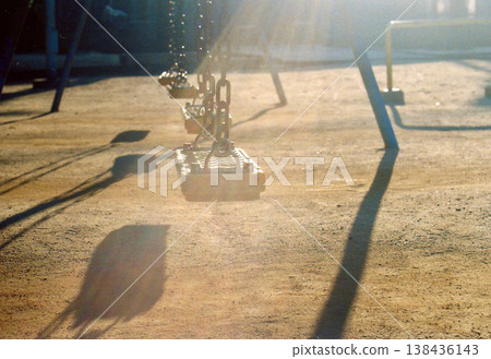 黃昏時的公園;鞦韆的輪廓在逆光下顯現。 黃昏時的公園;鞦韆的輪廓在逆光下顯現。 138436143