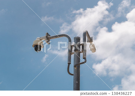 Security surveillance cameras mounted on metal pole against blue sky with clouds 138436227