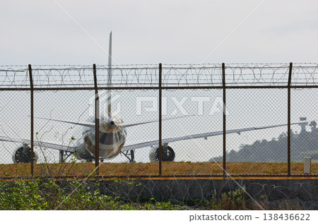 A huge passenger plane pulls onto the runway of Thailand airport, a view through the fence A huge passenger plane pulls onto the runway of Thailand airport, a view through the fence 138436622