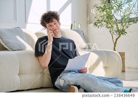 Young handsome guy, 20s university student talking on cell phone with paper documents 138436649