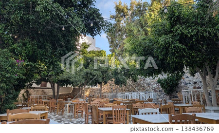 Many tables and chairs in an outdoor restaurant surrounded by stone walls and trees in the old town Many tables and chairs in an outdoor restaurant surrounded by stone walls and trees in the old town 138436769