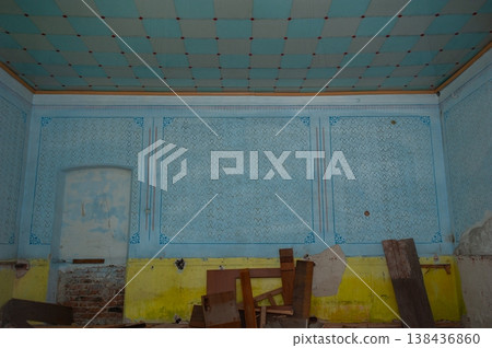 Abandoned Vintage Room With Blue Checkered Ceiling And Yellow Walls Showing Signs Of Decay And Forgotten Wooden Furniture Pieces 138436860