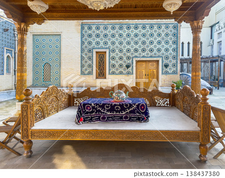 Traditional Uzbek tapchan, Ornate wooden bed rests beneath carved ceiling 138437380