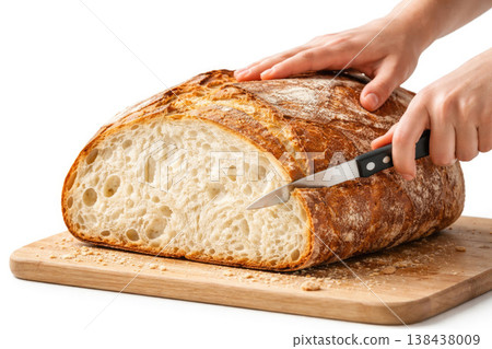 The hand is cutting a large bread on a wooden board. The hand is cutting a large bread on a wooden board. 138438009