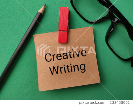 Conceptual flat lay on a vibrant green background featuring the words Creative Writing printed on a brown paper note. Conceptual flat lay on a vibrant green background featuring the words Creative Writing printed on a brown paper note. 138438091