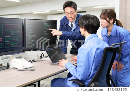 A veteran engineer shares his screen with a junior engineer while making program modifications. 138438165