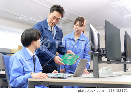An engineering team conducting technical training while checking printed circuit boards. 138438171