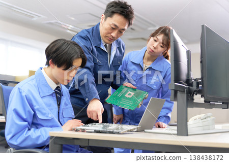Technical training for young employees learning by looking at circuit boards, with their supervisors providing guidance. Technical training for young employees learning by looking at circuit boards, with their supervisors providing guidance. 138438172
