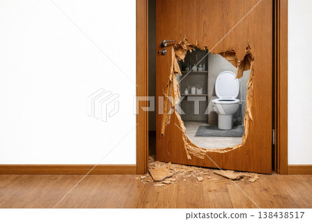 A broken wooden door with a hole and a view of the toilet. Space for text. A broken wooden door with a hole and a view of the toilet. Space for text. 138438517