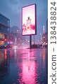 Glowing pink perfume billboard with gerbera flowers reflecting in a wet city street on a rainy evening 138438824