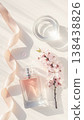 Luxurious pink perfume bottle with a silk ribbon and spring cherry blossoms in soft morning sunlight 138438826