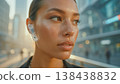 Portrait of a woman with freckles and a transparent futuristic earbud in a sunset city bokeh light 138438832
