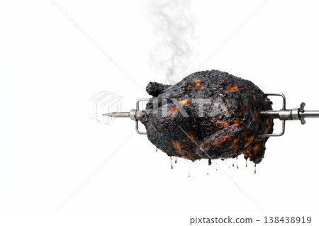 Burnt chicken on a spit with smoke on a light background. Space for text. Burnt chicken on a spit with smoke on a light background. Space for text. 138438919