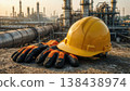 Yellow hardhat and gloves rest at industrial refinery 138438974