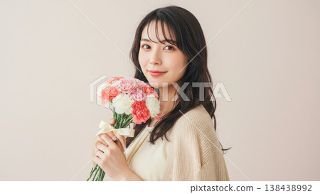 一幅肖像畫,畫中一位面帶微笑的女子手捧一束用絲帶紮好的康乃馨。 一幅肖像畫,畫中一位面帶微笑的女子手捧一束用絲帶紮好的康乃馨。 138438992