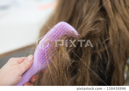Hand combing tangled brown hair with a purple brush Hand combing tangled brown hair with a purple brush 138438996