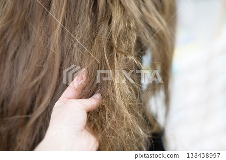 Hand touching dry damaged tangled brown hair 138438997