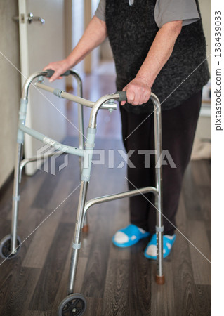 Senior woman walking at home in rehabilitation with medical walkers. Senior woman walking at home in rehabilitation with medical walkers. 138439033