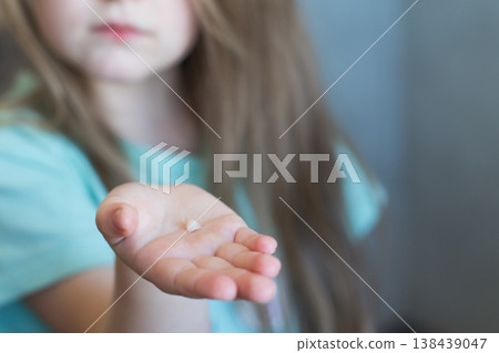 Little cute blonde girl child holding and showing her fallen milk front tooth in hands Little cute blonde girl child holding and showing her fallen milk front tooth in hands 138439047
