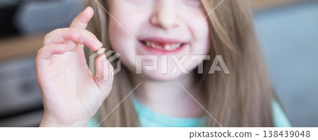 Little cute blonde girl child holding and showing her fallen milk front tooth in hands Little cute blonde girl child holding and showing her fallen milk front tooth in hands 138439048
