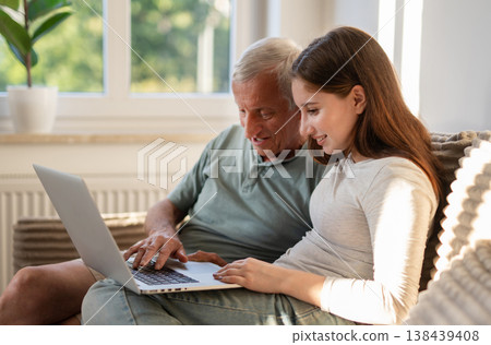 Girl With Granddad Browsing Social Media Together And Having Fun On A Sofa At Home Girl With Granddad Browsing Social Media Together And Having Fun On A Sofa At Home 138439408