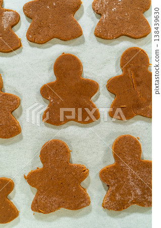 A tray of freshly baked Orange Zest Gingerbread Cookies in gingerbread girl shapes cooling on parchment paper. The close-up perspective highlights their golden-brown texture. A tray of freshly baked Orange Zest Gingerbread Cookies in gingerbread girl shapes cooling on parchment paper. The close-up perspective highlights their golden-brown texture. 138439630