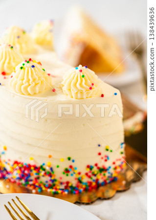 A vertical shot of a vanilla birthday cake slice with bright sprinkles and frosting on a white plate. The image has a soft, celebratory aesthetic with pastel lighting. A vertical shot of a vanilla birthday cake slice with bright sprinkles and frosting on a white plate. The image has a soft, celebratory aesthetic with pastel lighting. 138439636