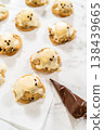 Overhead view of iced cookies arranged on parchment paper with a piping bag nearby. The bright background and soft lighting create a clean cookie decorating layout. 138439665