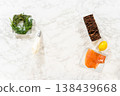 A top view of fresh herbs a piping bag with a metal tip smoked salmon crispbread crackers and a lemon arranged on a marble surface before assembling canapes 138439668
