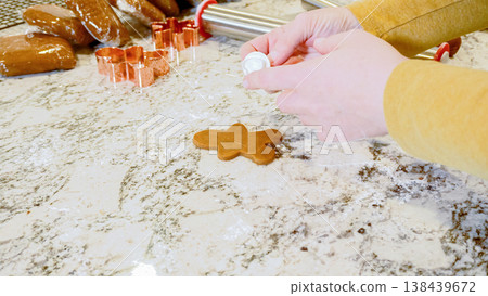 Using various festive cookie cutters, we're cutting out charming gingerbread cookies from the rolled dough on the sleek marble counter, bringing holiday cheer to the modern kitchen. Using various festive cookie cutters, we're cutting out charming gingerbread cookies from the rolled dough on the sleek marble counter, bringing holiday cheer to the modern kitchen. 138439672