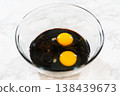 A bowl filled with molasses and two large eggs for Spiced Gingerbread Cookie Dough Perfect for Baking. The dark molasses contrasts with the bright yolks, creating a rich base for the dough. 138439673
