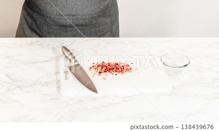Fresh cranberries are finely chopped on a cutting board, prepared for adding to the cranberry buttercream in the lemon spritz cookie recipe. 138439676