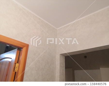 Minimalist home interior featuring textured beige wallpaper, a wooden door frame, and clean ceiling 138440576
