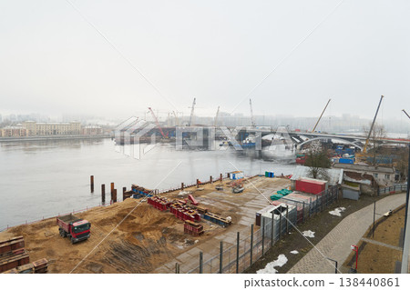 Large cranes hoist steel beams over water at construction site Large cranes hoist steel beams over water at construction site 138440861