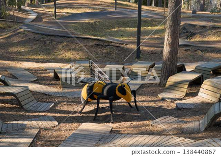 Contemporary Metal Bee Artwork. Modern Metal Bee Sculpture Situated Amidst Layered Forest Shadows Contemporary Metal Bee Artwork. Modern Metal Bee Sculpture Situated Amidst Layered Forest Shadows 138440867