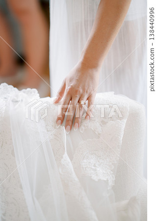 Bride Smoothing Lace Gown During Prep 138440996