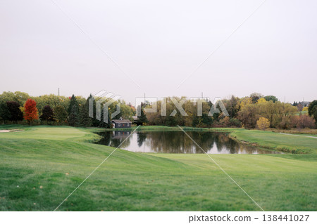 Calm Lake Mirrors Vibrant Fall Trees With Gentle Grassy Bank Calm Lake Mirrors Vibrant Fall Trees With Gentle Grassy Bank 138441027