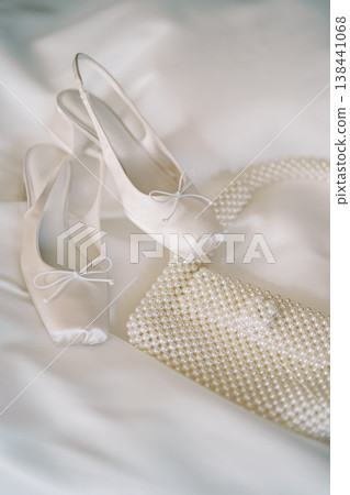 Chic Satin Shoes And Matching Clutch Featuring Bow And Pearl Adornments On Silk Background 138441068