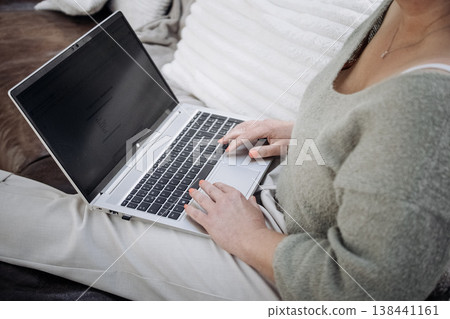 Person Typing On Laptop While Sitting On Sofa: Relaxed Remote Work And Online Browsing In Cozy Living Room At Home Person Typing On Laptop While Sitting On Sofa: Relaxed Remote Work And Online Browsing In Cozy Living Room At Home 138441161