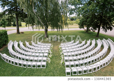Serene Garden Setting With White Chairs And Blooming Flowers Serene Garden Setting With White Chairs And Blooming Flowers 138441365