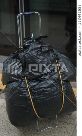 A cart carrying luggage wrapped in black bags A cart carrying luggage wrapped in black bags 138441682