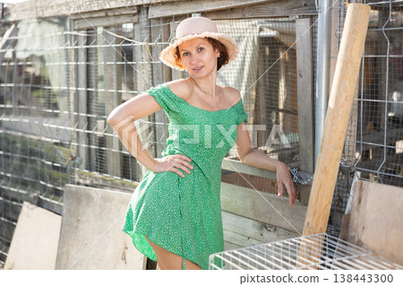 Young girl with bare shoulders stands against background of vegetable garden, poses in countryside Young girl with bare shoulders stands against background of vegetable garden, poses in countryside 138443300