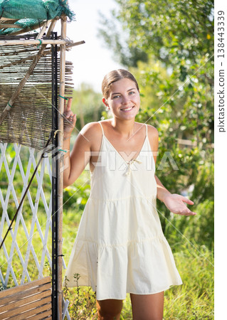 Female peasant girl stands near garden bed, near chicken coop and enjoys country activities Female peasant girl stands near garden bed, near chicken coop and enjoys country activities 138443339