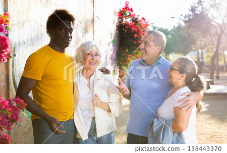 A group of friendly multiracial mixed-sex mature adult people standing outside talking to each other A group of friendly multiracial mixed-sex mature adult people standing outside talking to each other 138443370