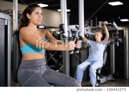 Young girl exercising chest muscles on butterfly machine 138443373