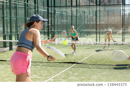 Young sporty woman playing padel game in court on sunny day 138443375